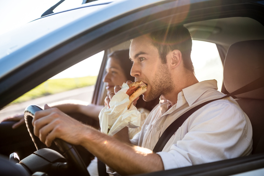 Couple in car - man is driving and eating baguette