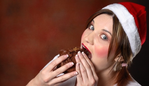 Santa girl with red cheeks eating a piece of chocolate cake