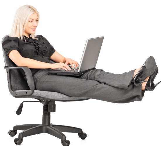 Young woman sitting on office chair with her legs up and working