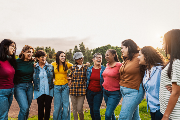Diverse group of women standing together outdoors, smiling and supporting each other, representing community and connection for women with PCOS