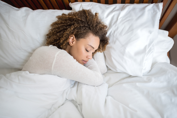 Woman sleeping peacefully in bed, representing the importance of quality sleep in managing PCOS symptoms 
