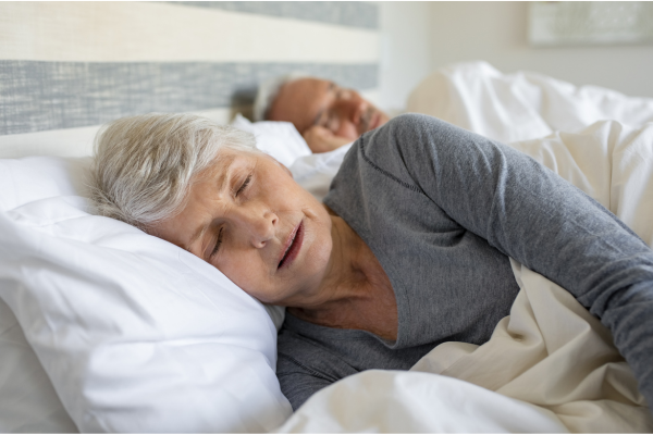 Older woman sleeping peacefully in bed, illustrating the importance of sleep for healthy aging"