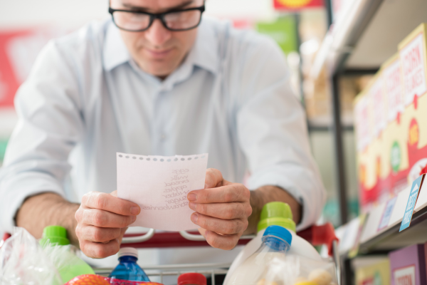 Man reviewing a grocery list while shopping, preparing for a GLP-1 medication plan with healthier food choices and intentional nutrition.