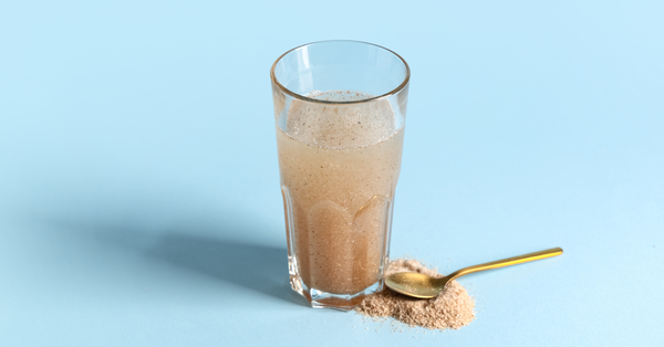 Glass of psyllium fiber supplement mixed with water next to spoonful of powder