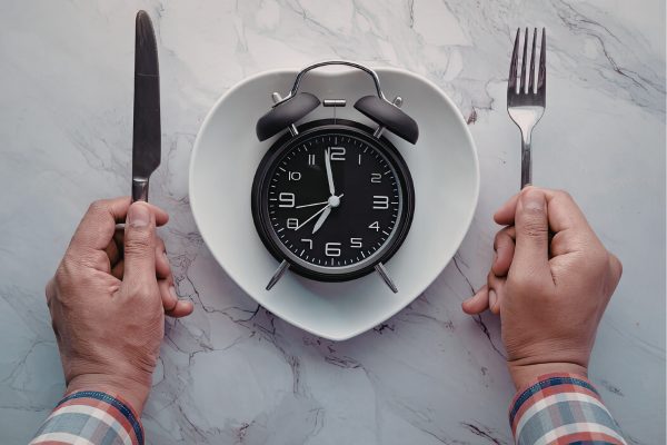 Clock on a plate representing meal timing and protein distribution across breakfast, lunch, and dinner.